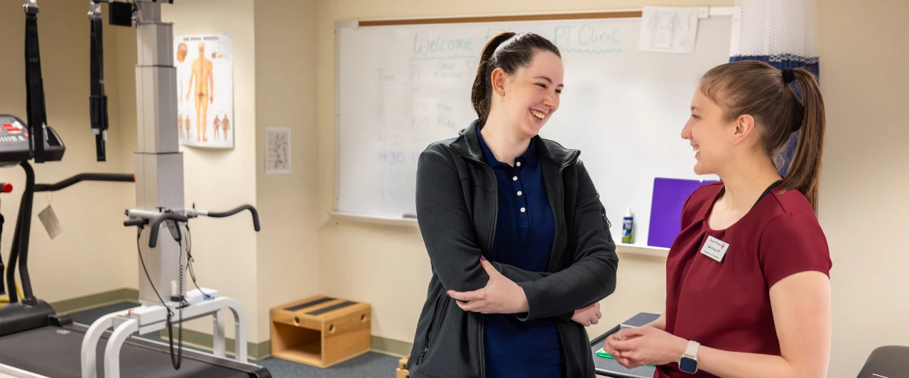 Two Scranton students smiling and talking to each other in the Leahy physical therapy clinic