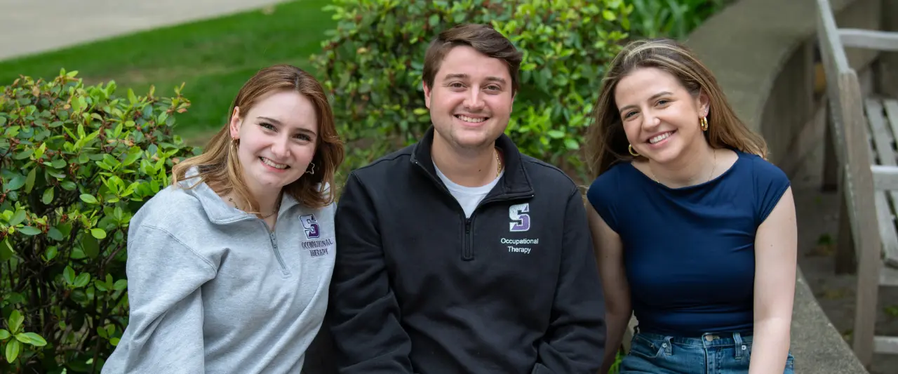 Three smiling Scranton students sitting outdoors together