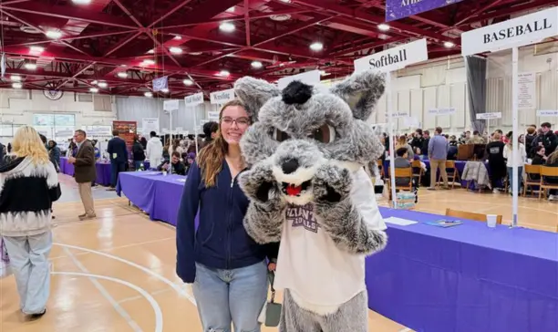 University of Scranton student posing with Iggy, the school mascot, at the campus open house event in the gym
