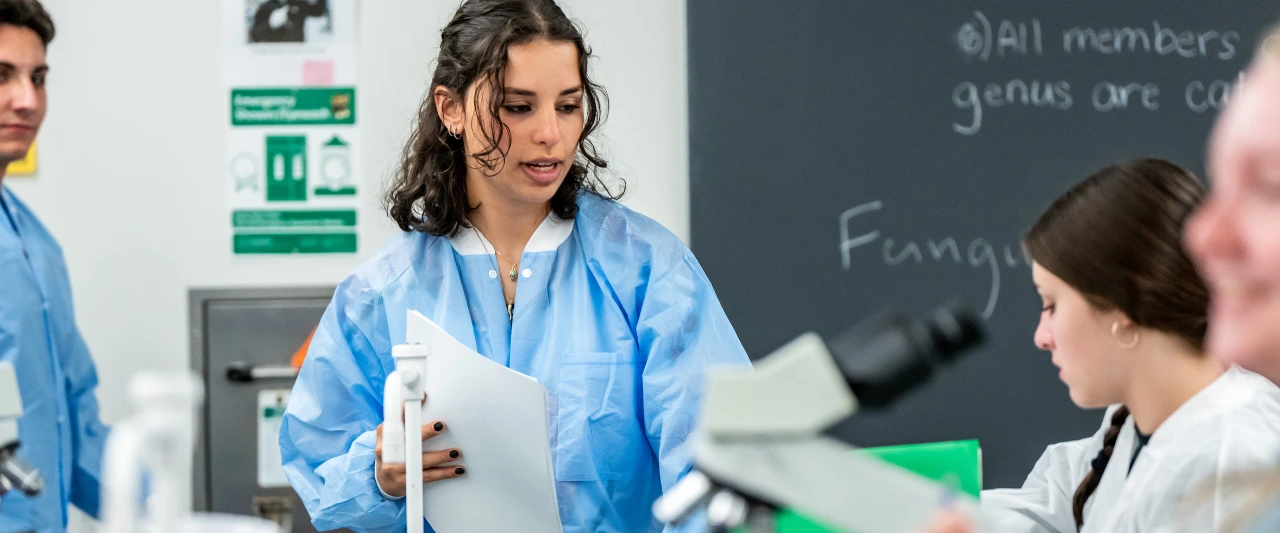 Scranton students wearing protective gowns and lab coats working in a science laboratory