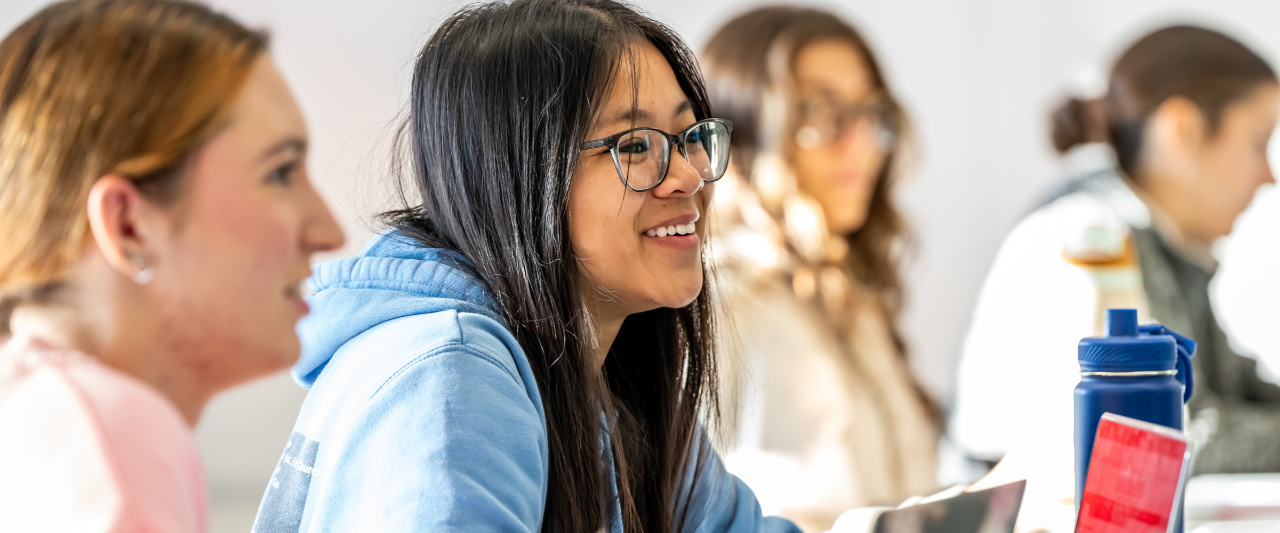 A smiling Scranton female student sitting at a desk in a classroom