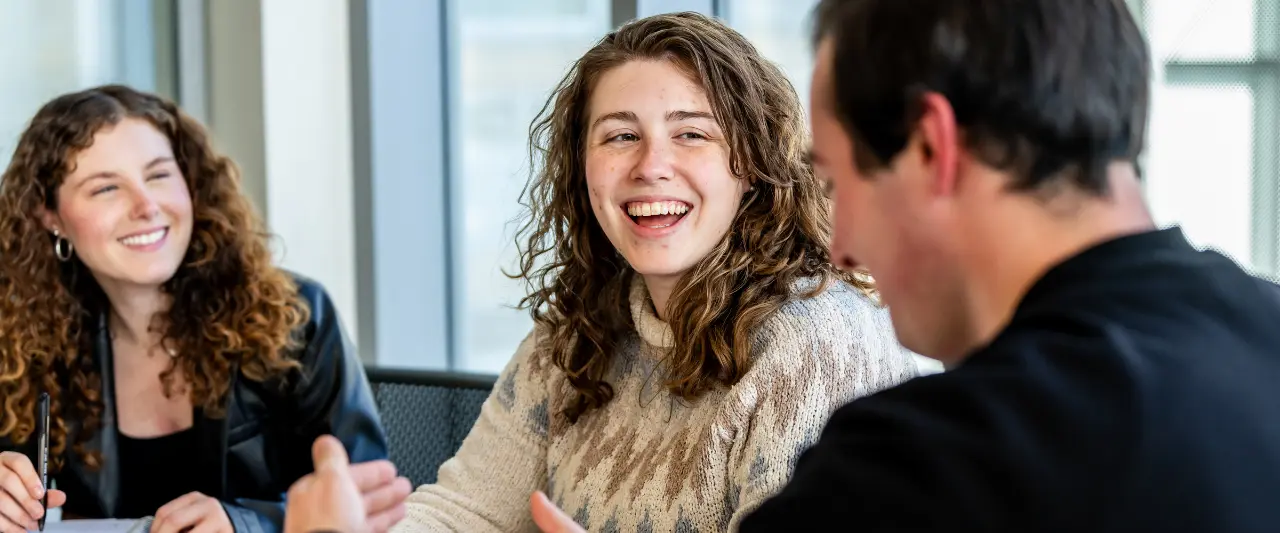 Three Scranton students engage in a lively conversation in a study room